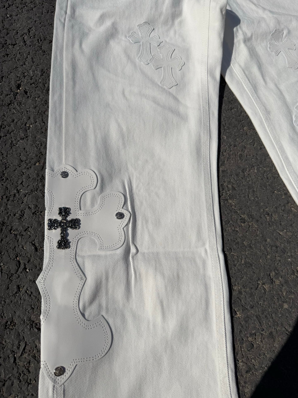 White denim pants with small embroidered floral motifs and button details