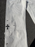 White denim pants with small embroidered floral motifs and button details