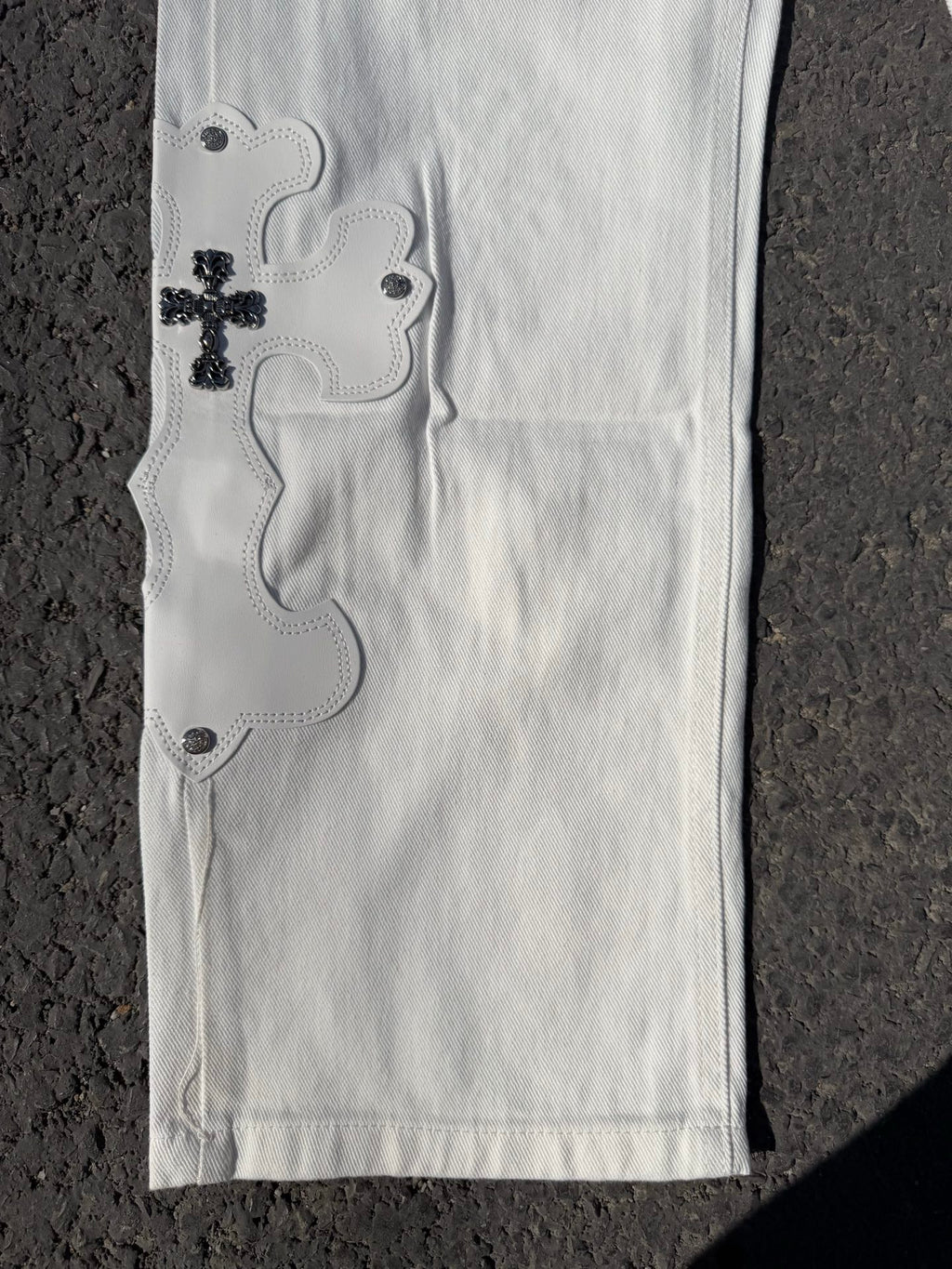 White denim pants with side embroidery and dark button accents along the hem