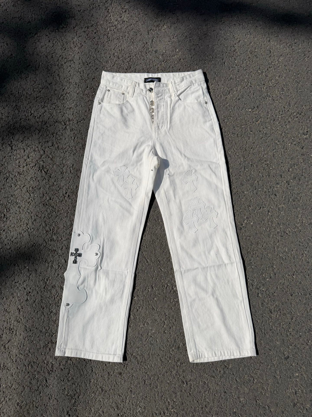 White denim pants with lace-like floral embroidery on the legs and straight cut