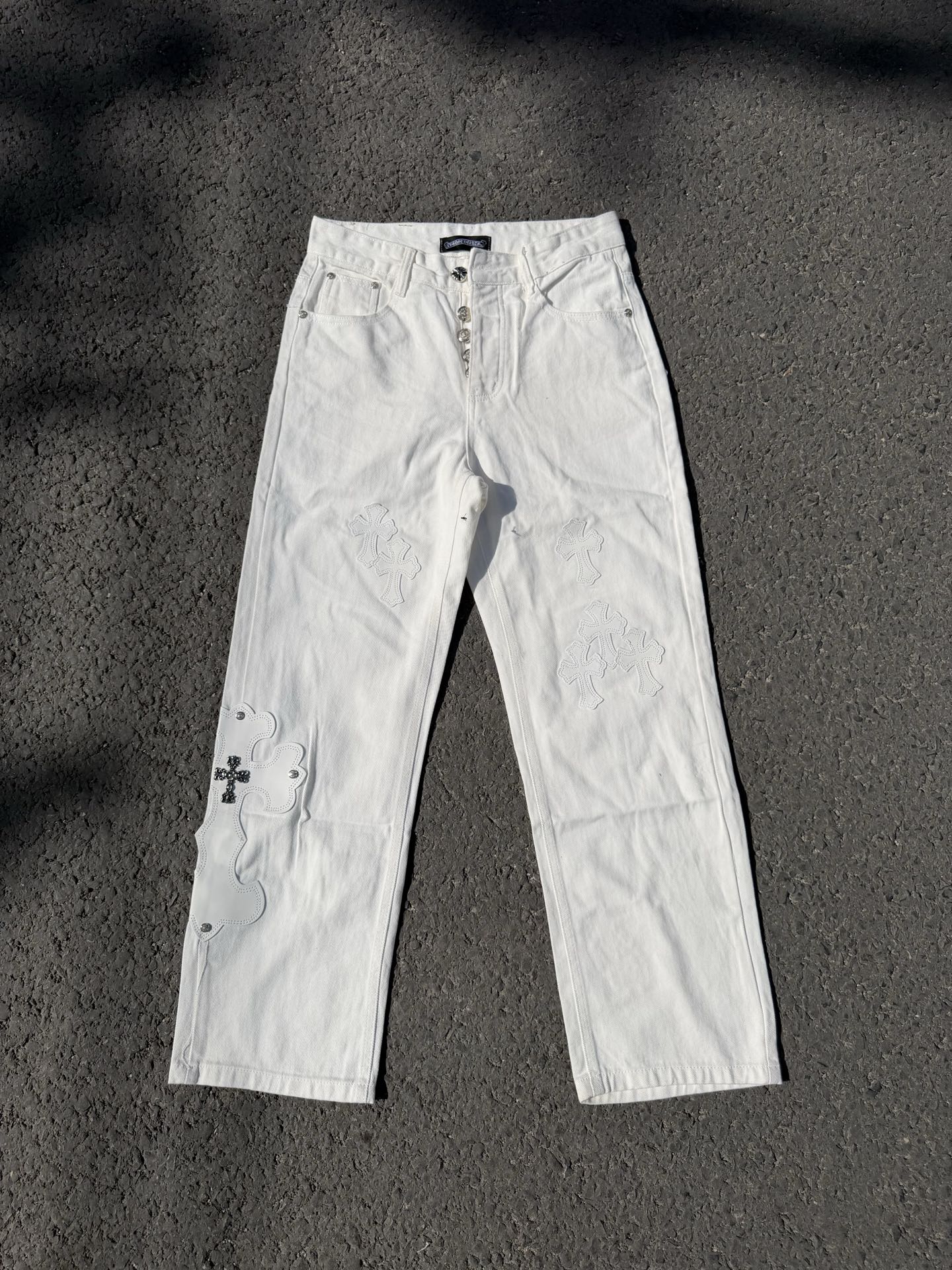 White denim pants with lace-like floral embroidery on the legs and straight cut