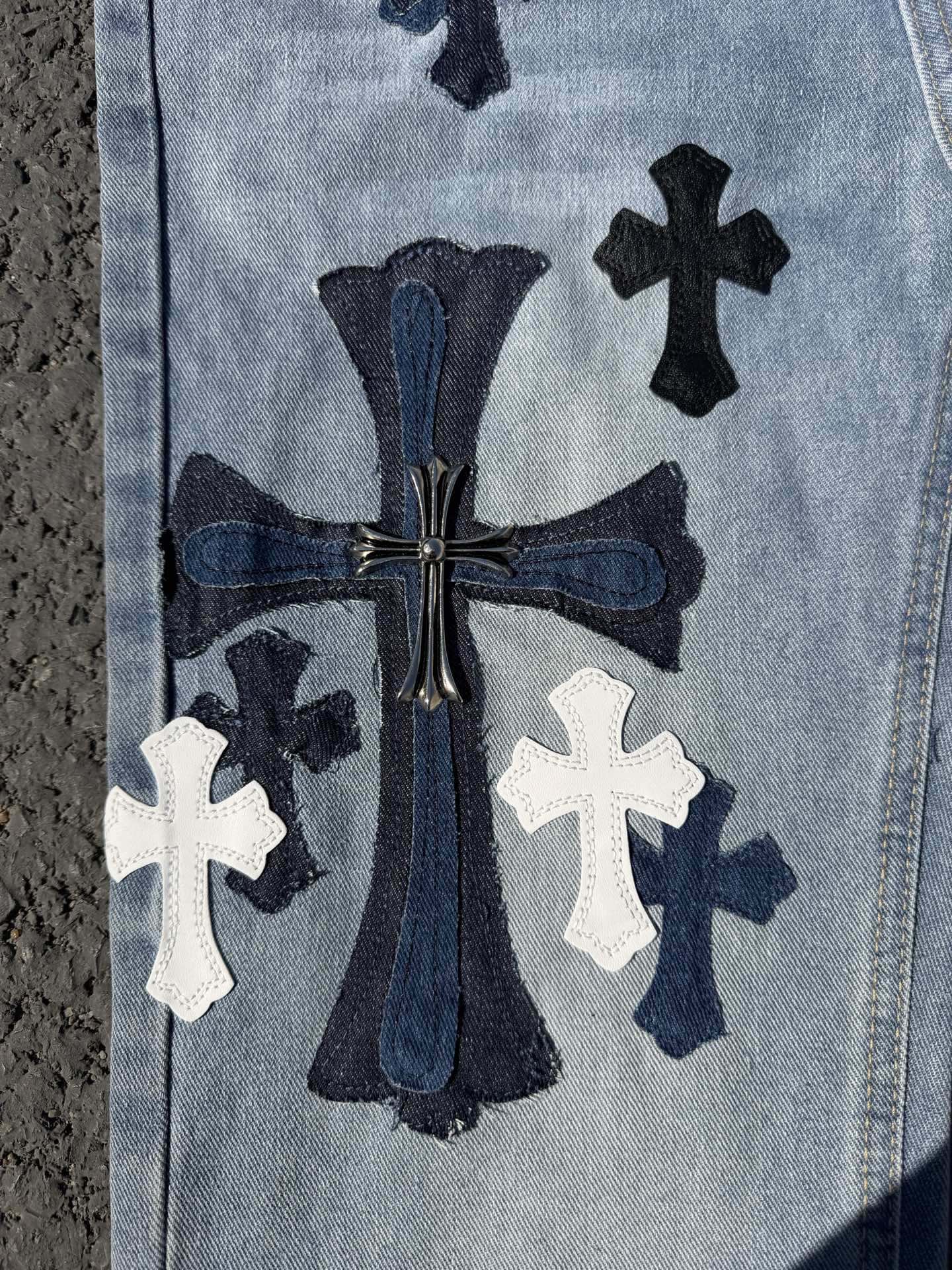 Light wash denim pants with ornate center graphic and white cross patches