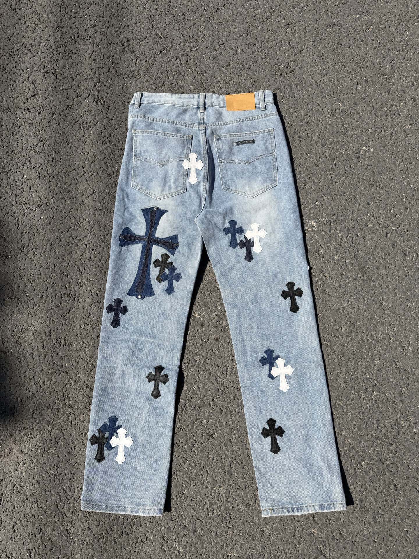 Light wash denim pants with scattered cross patches and back pockets