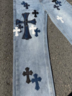 Light wash denim pants with large cross applique and central cross pattern