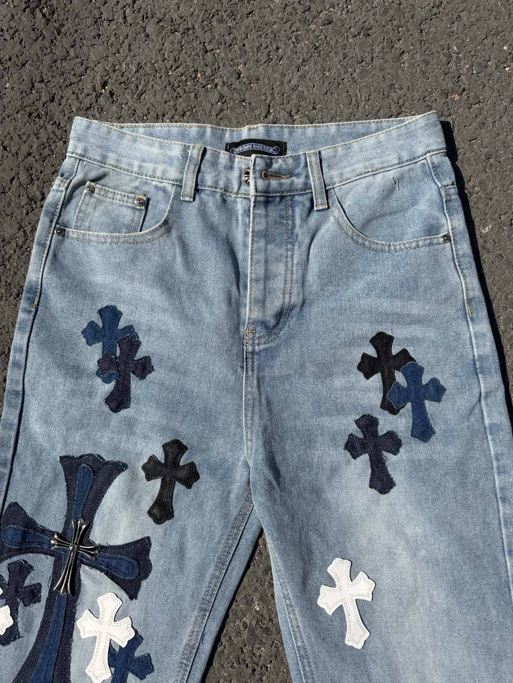 Light wash denim pants with front pockets and navy cross appliques