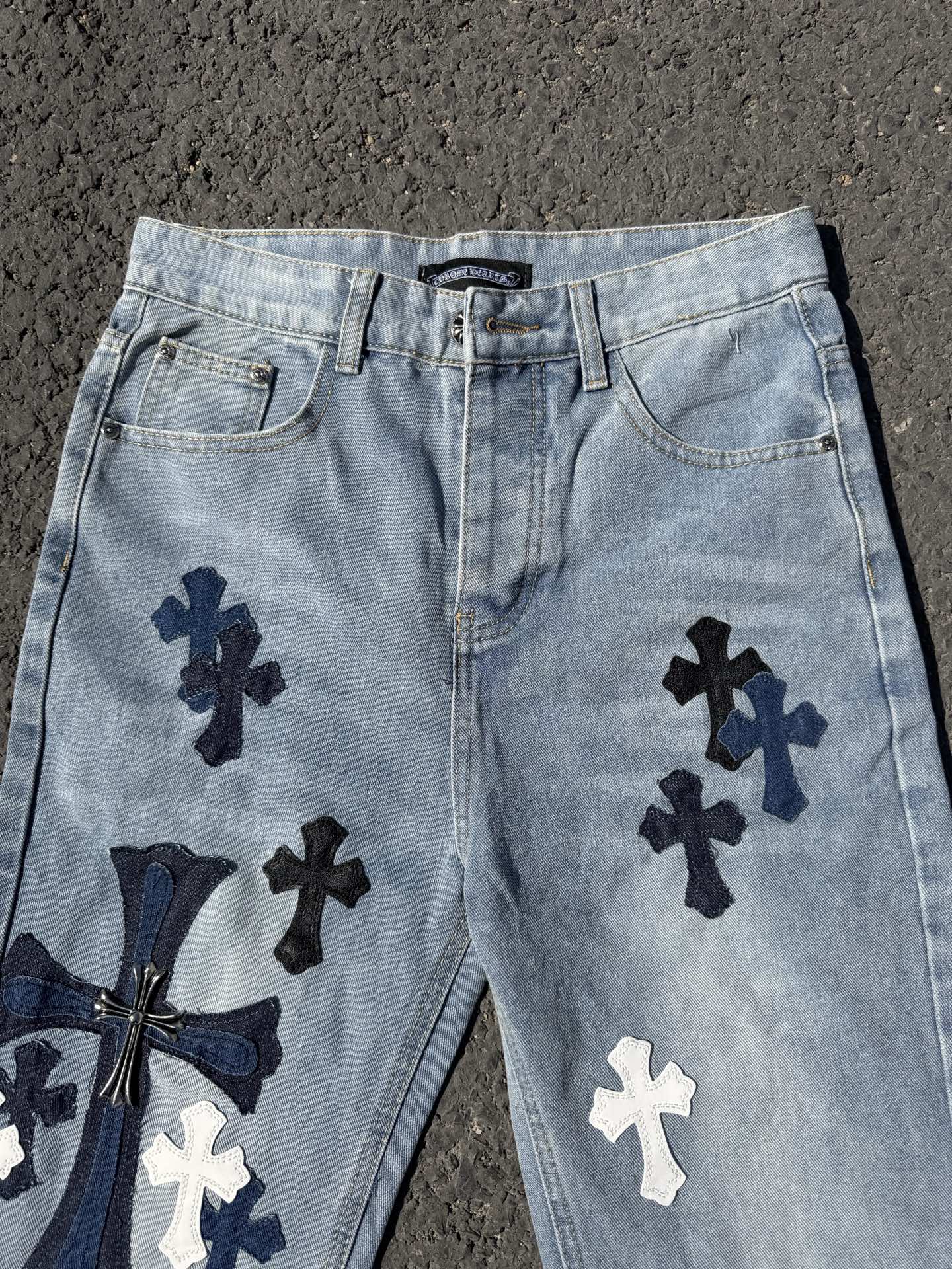 Light wash denim pants with front pockets and navy cross appliques