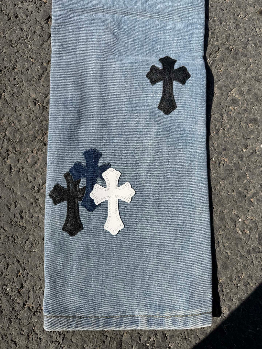Light blue denim pants lower legs with dark and white cross patches