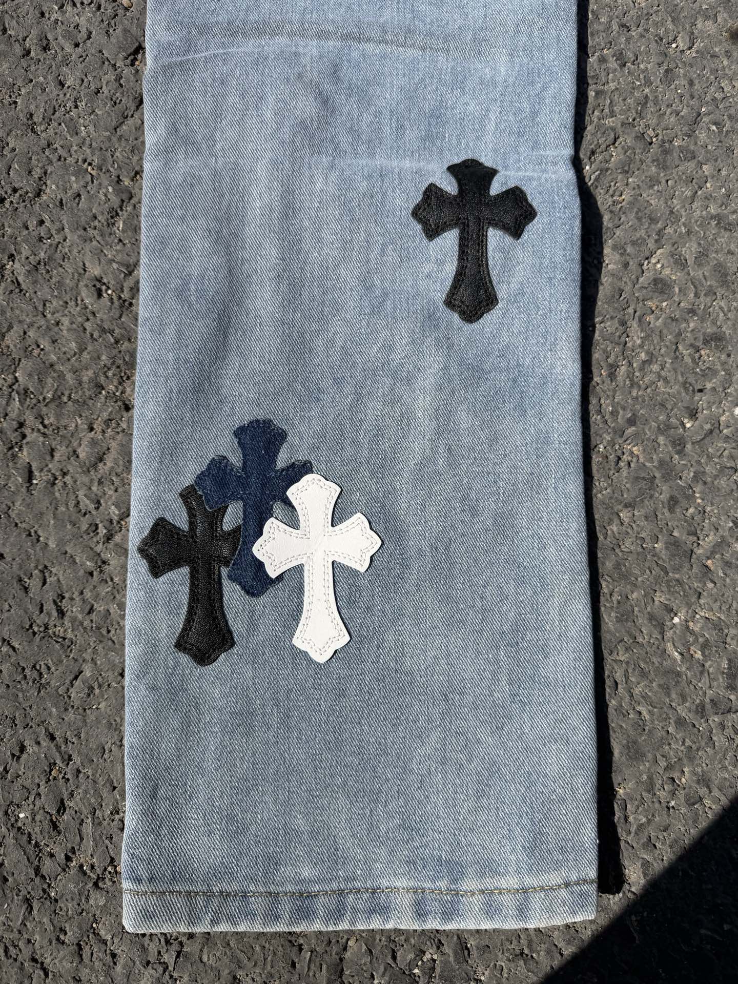 Light blue denim pants lower legs with dark and white cross patches