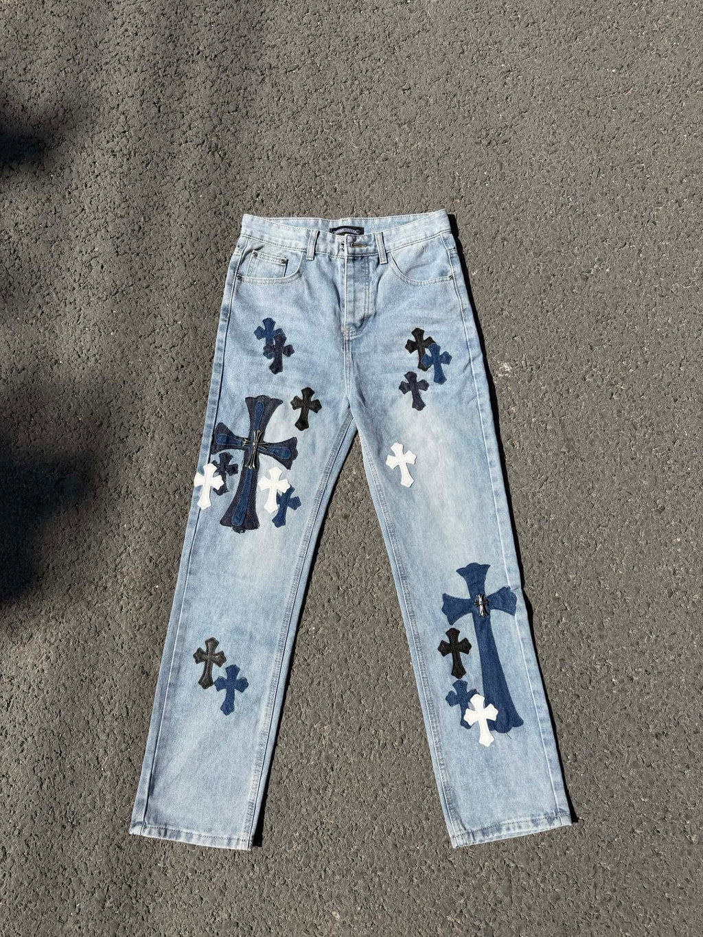 Light wash denim pants with navy cross graphics, straight leg, belt loops