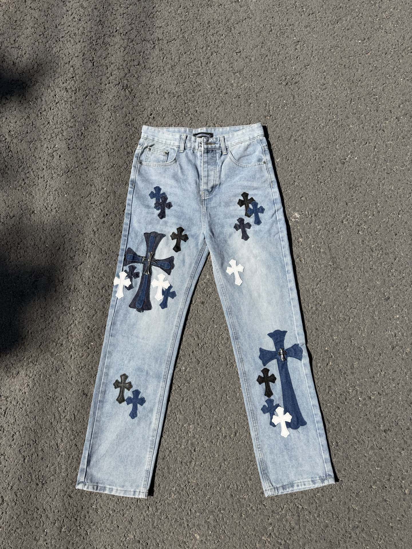 Light wash denim pants with navy cross graphics, straight leg, belt loops