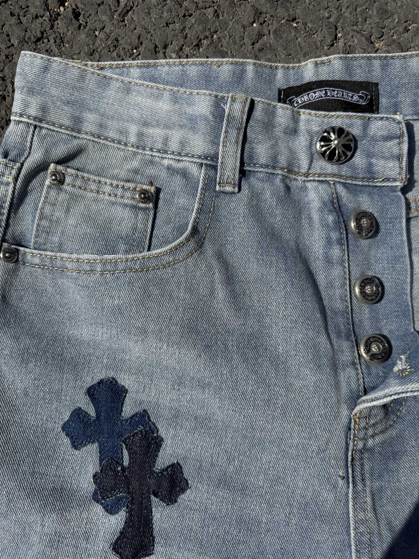 Light wash denim pants with front button placket and navy cross patch on pocket