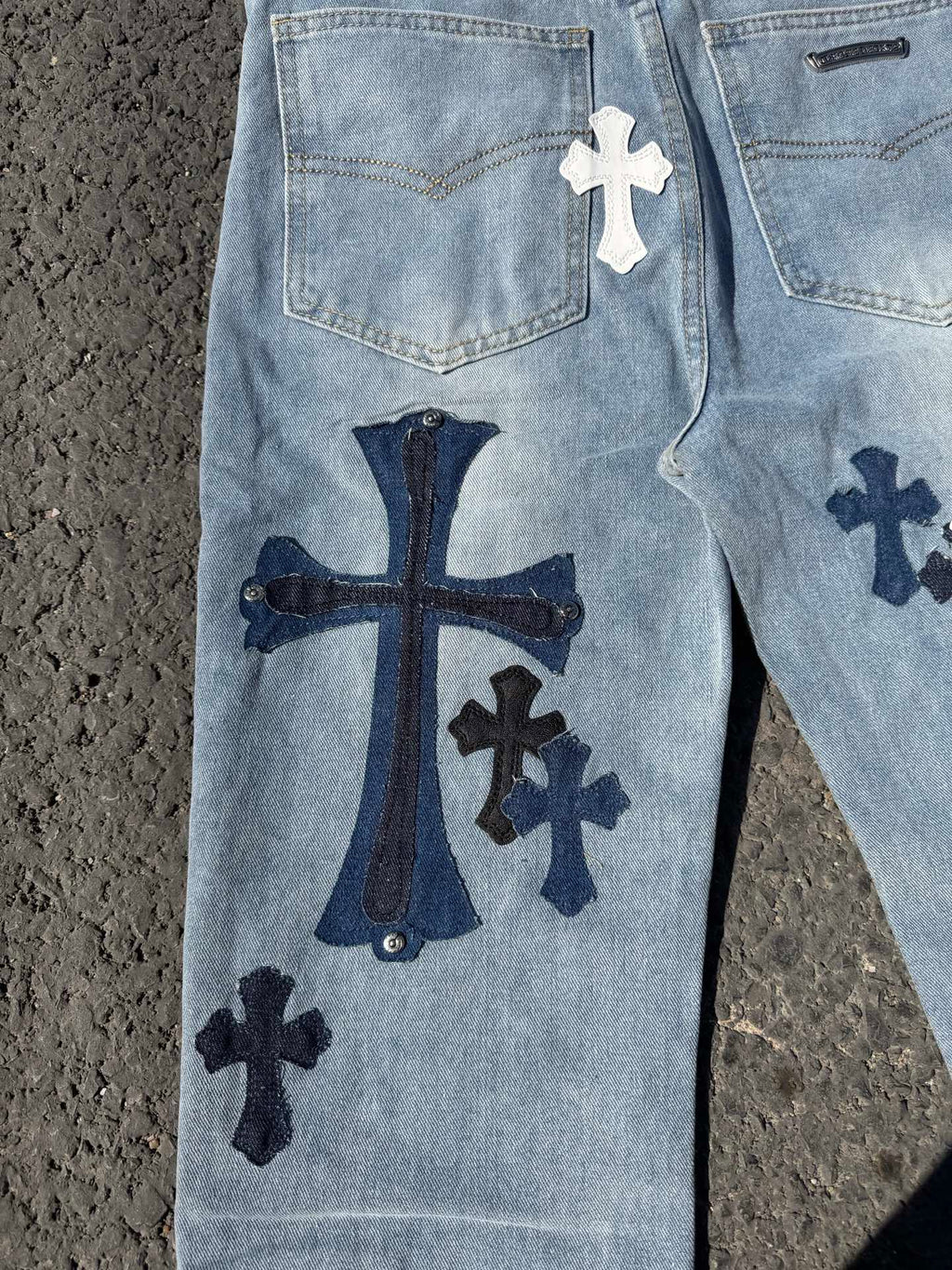 Light blue denim pants front with cross patches and coin pocket, zip fly