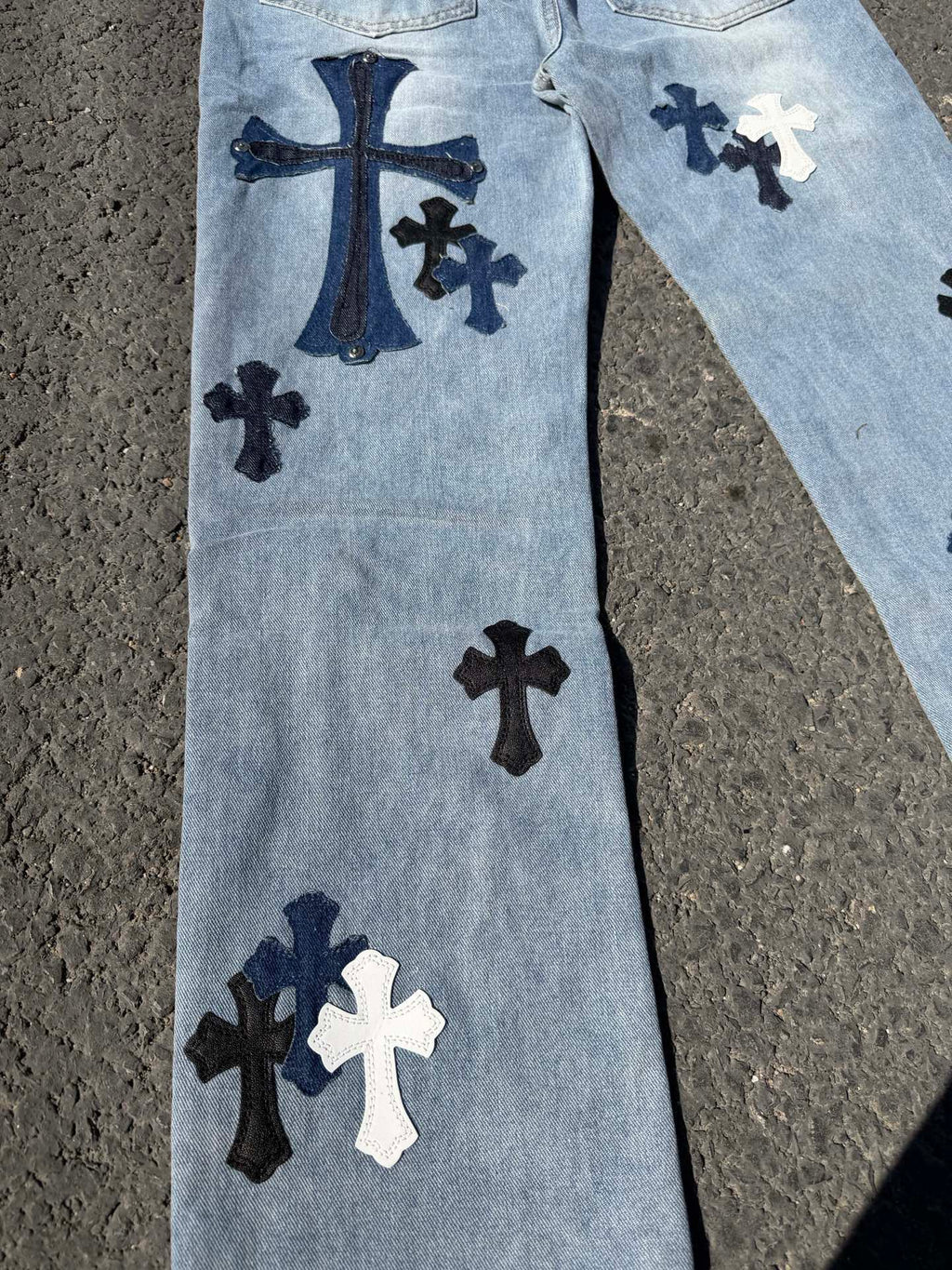Light blue denim pants with dark and white cross patches on front