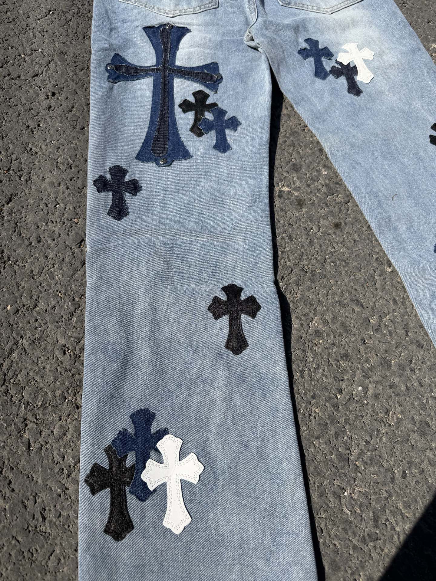 Light blue denim pants with dark and white cross patches on front