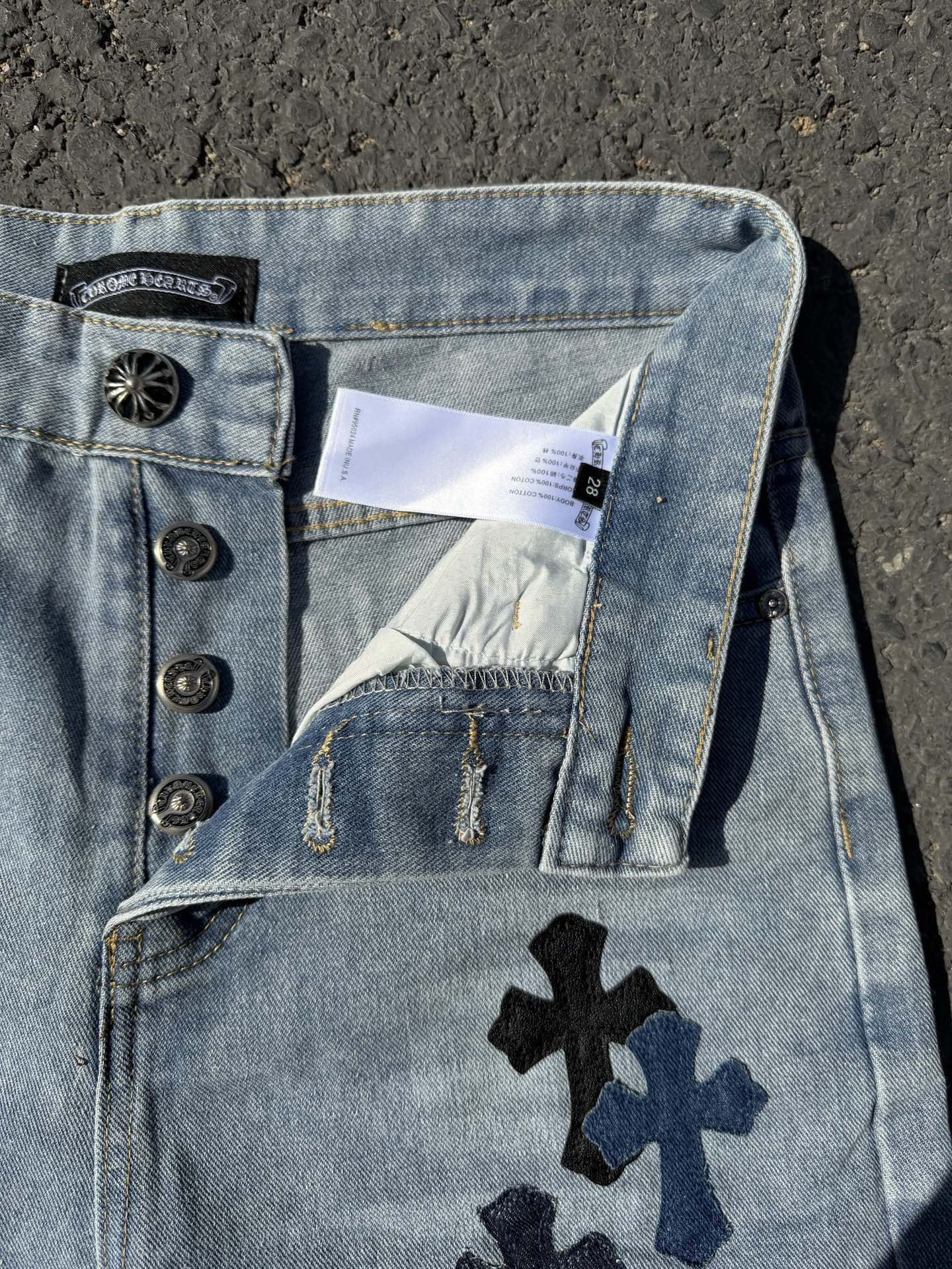 Light wash denim pants with snap waistband details and cross patch on back