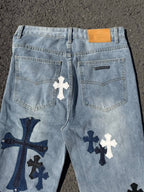 Light wash denim pants with front pockets, logo tab, and cross graphics