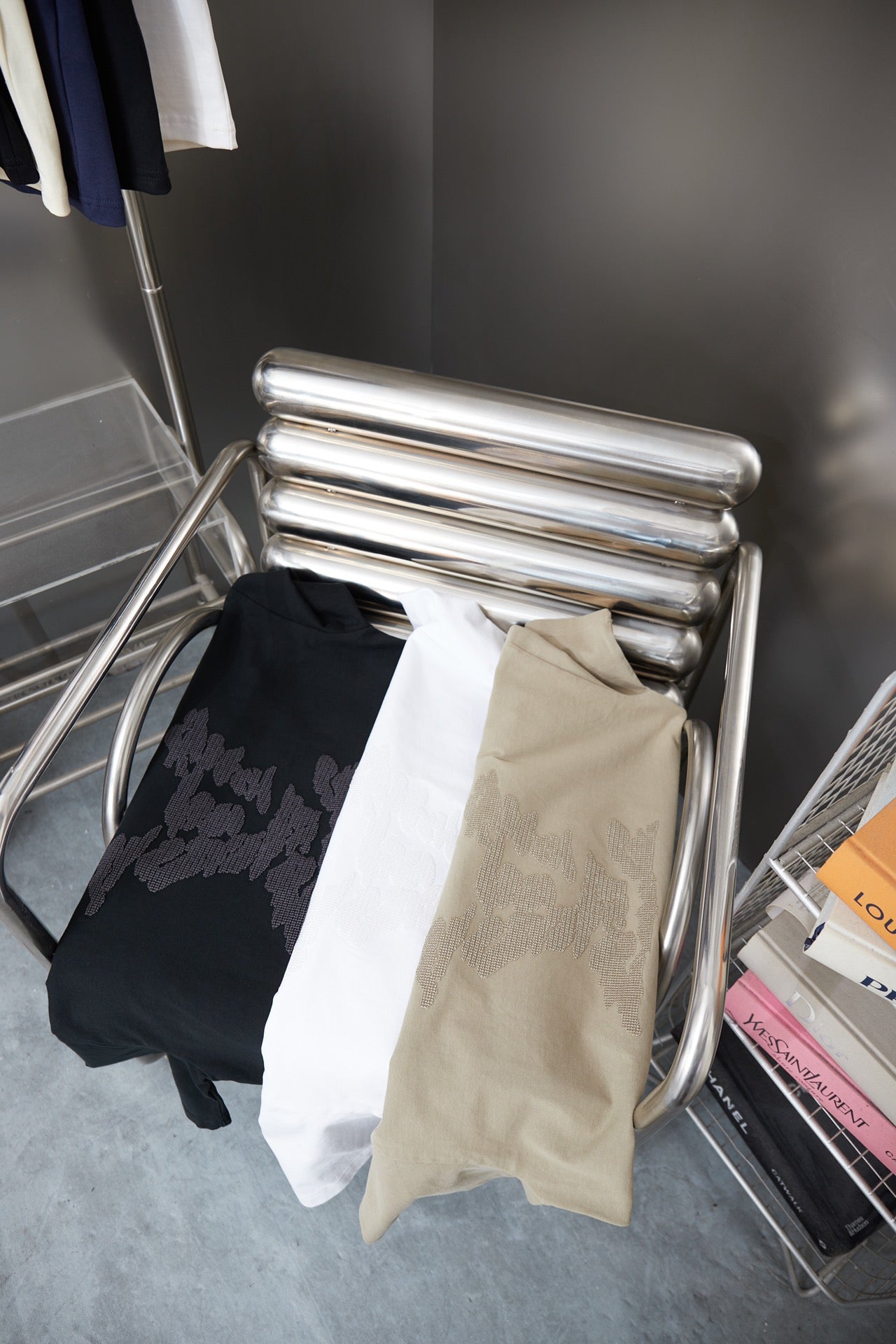 Stack of black and beige Louis Vuitton T-shirts on metal display rack