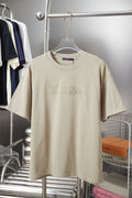 Beige Louis Vuitton graphic T-shirt on hanger with rhinestone-style LV lettering