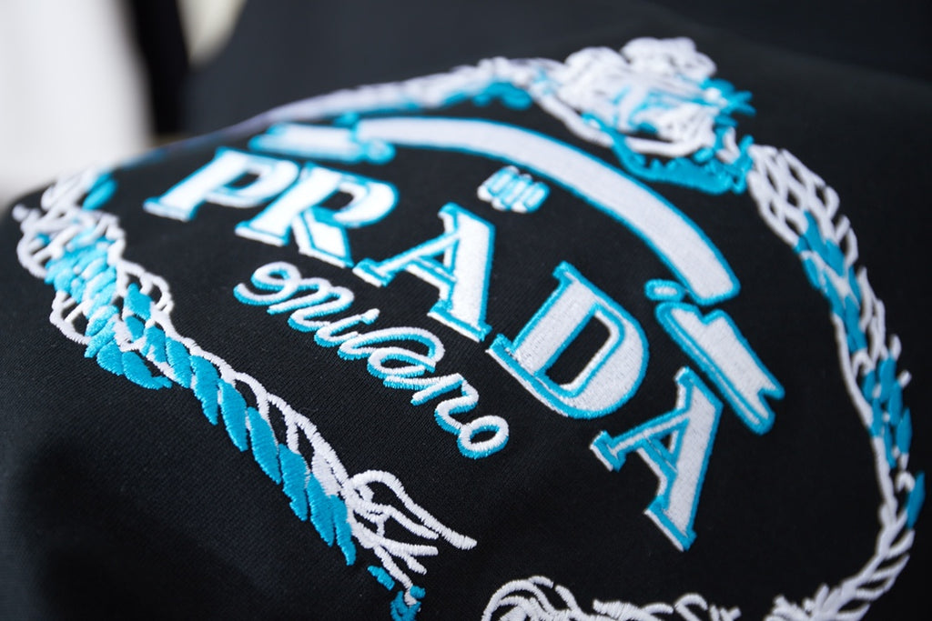 Black embroidered Prada Milano graphic with blue and white thread detail
