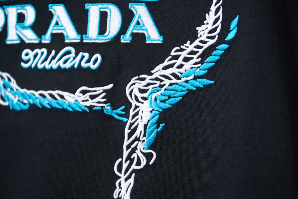 Embroidered PRADA Milano graphic on black T-shirt, close-up
