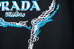 Embroidered PRADA Milano graphic on black T-shirt, close-up