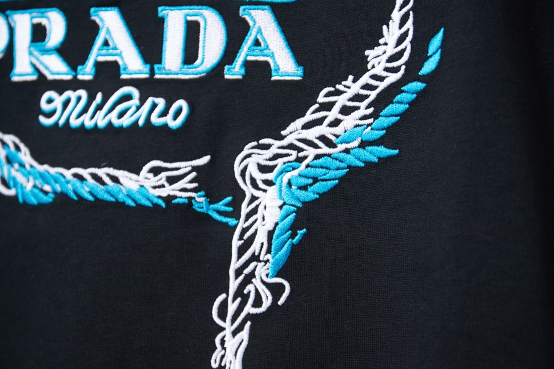 Embroidered PRADA Milano graphic on black T-shirt, close-up