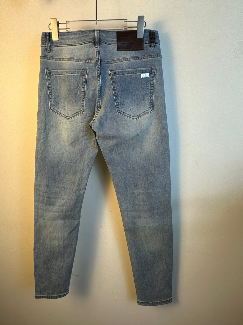 Light blue denim jeans with back yoke and five-pocket styling, hanging tag on waistband.