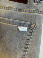 Light blue denim jeans pocket with embroidered DIOR label on stitched seam.