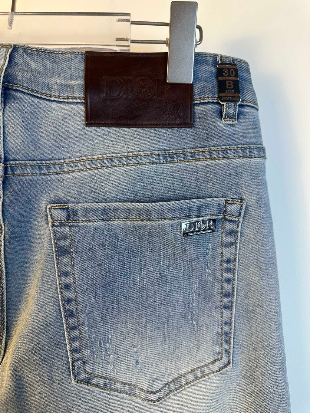 Light blue denim jeans with back pocket and stitched label, hanging Dior tag.