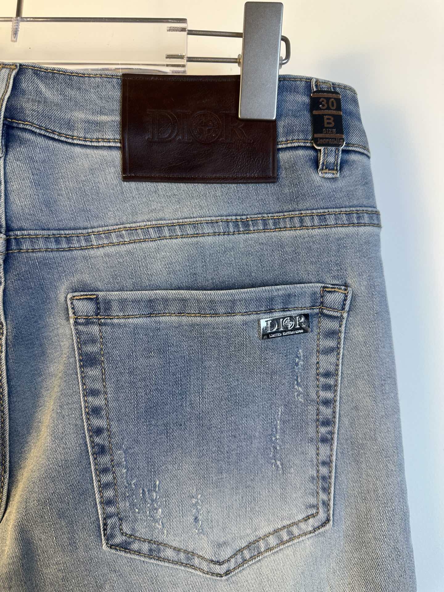 Light blue denim jeans with back pocket and stitched label, hanging Dior tag.