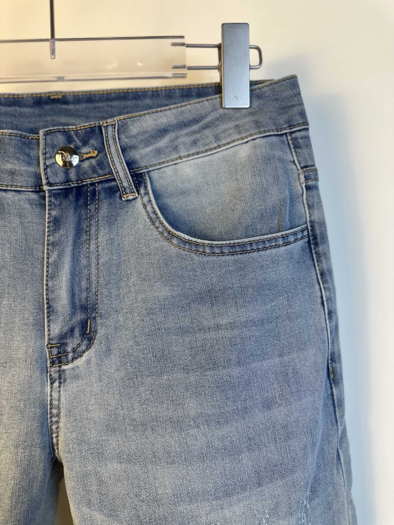 Light blue denim jeans with coin pocket and belt loops, hanging tag partially visible.