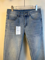 Light blue denim jeans with button fly and belt loops, hanging tag at front.