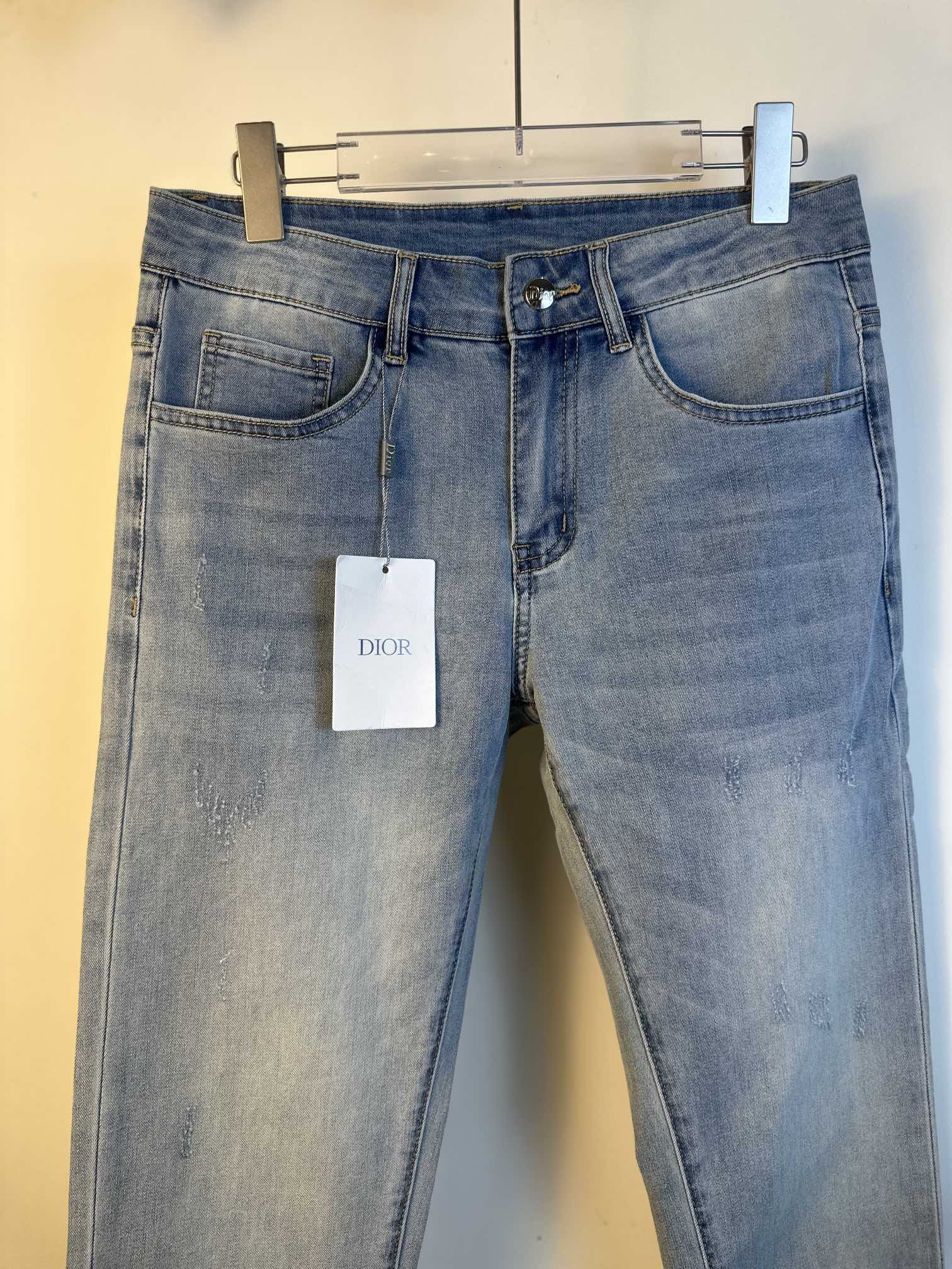 Light blue denim jeans with button fly and belt loops, hanging tag at front.