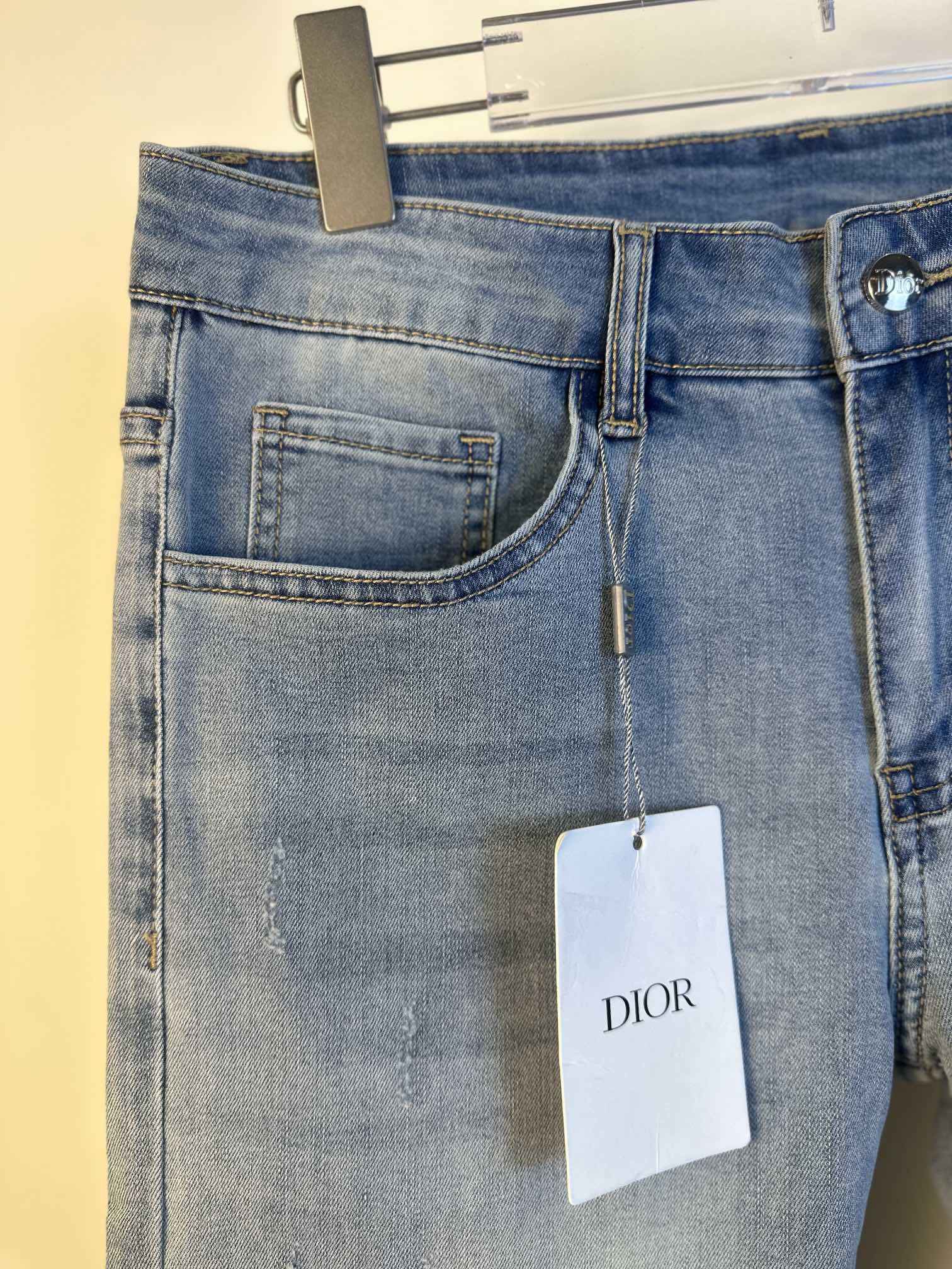 Light blue denim jeans front pocket detail with belt loops and hanging Dior tag.