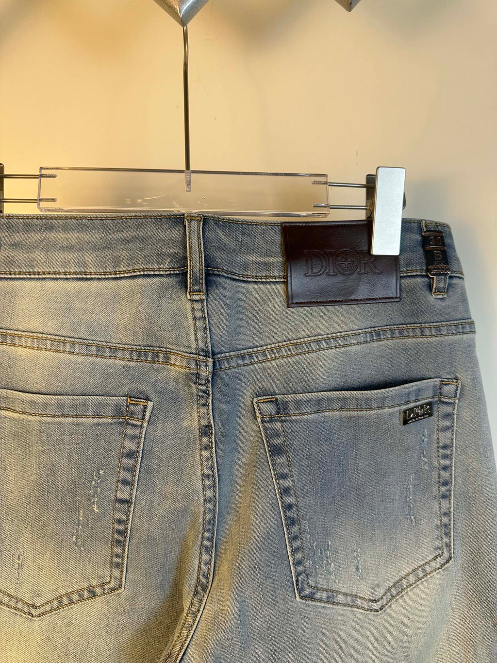 Light blue denim jeans back view with two rear pockets and belt loops, hanging tag.