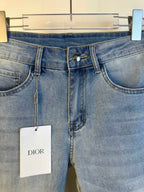 Light blue denim jeans close-up of waistband, button closure, and hanging Dior tag.