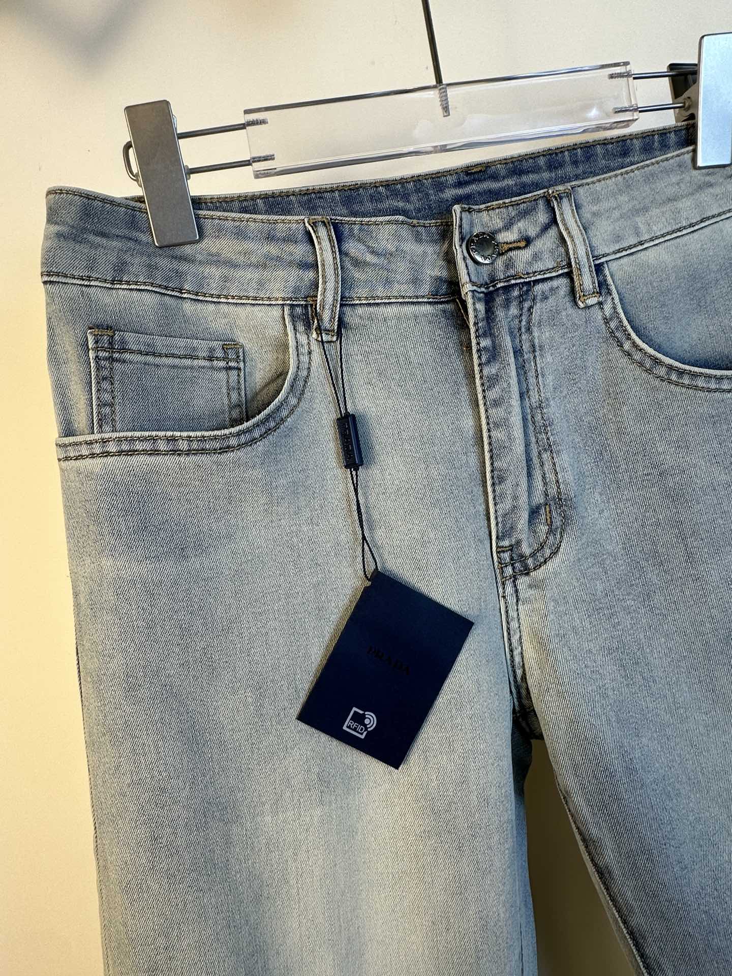 Light blue denim pants front, showing coin pocket, belt loops, and hanging tag