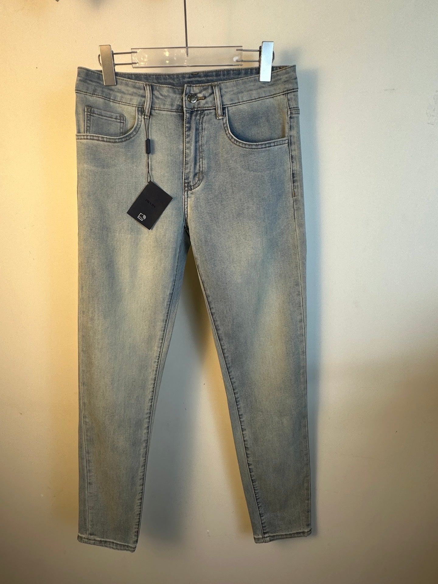 Light blue denim pants, full front view, with belt loops and hanging tag