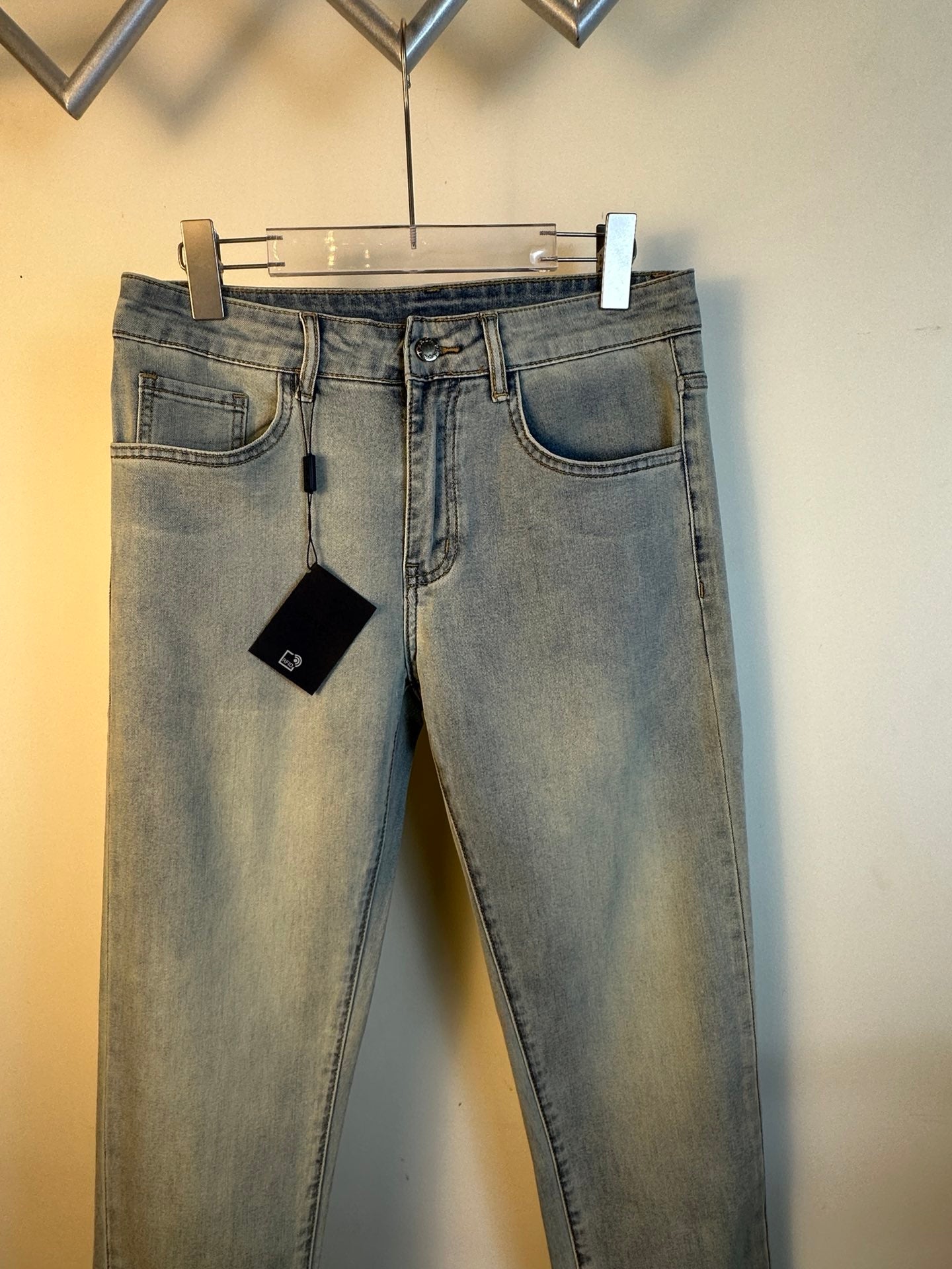 Light blue denim pants with belt loops, front pockets, and hanging tag