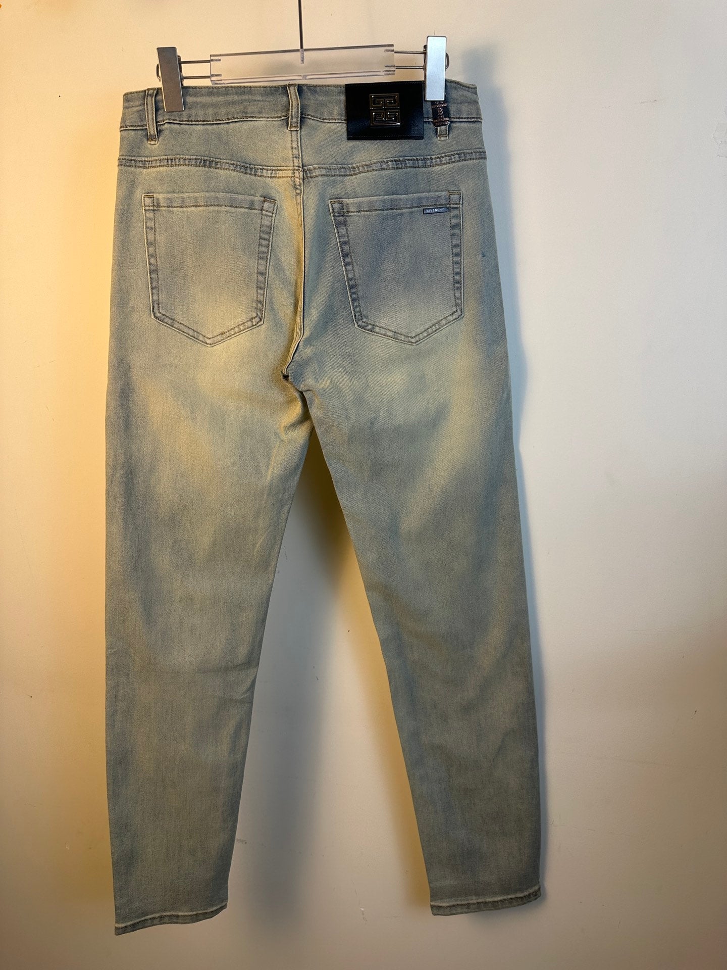 Light-wash denim jeans on a hanger with back pockets and belt loops