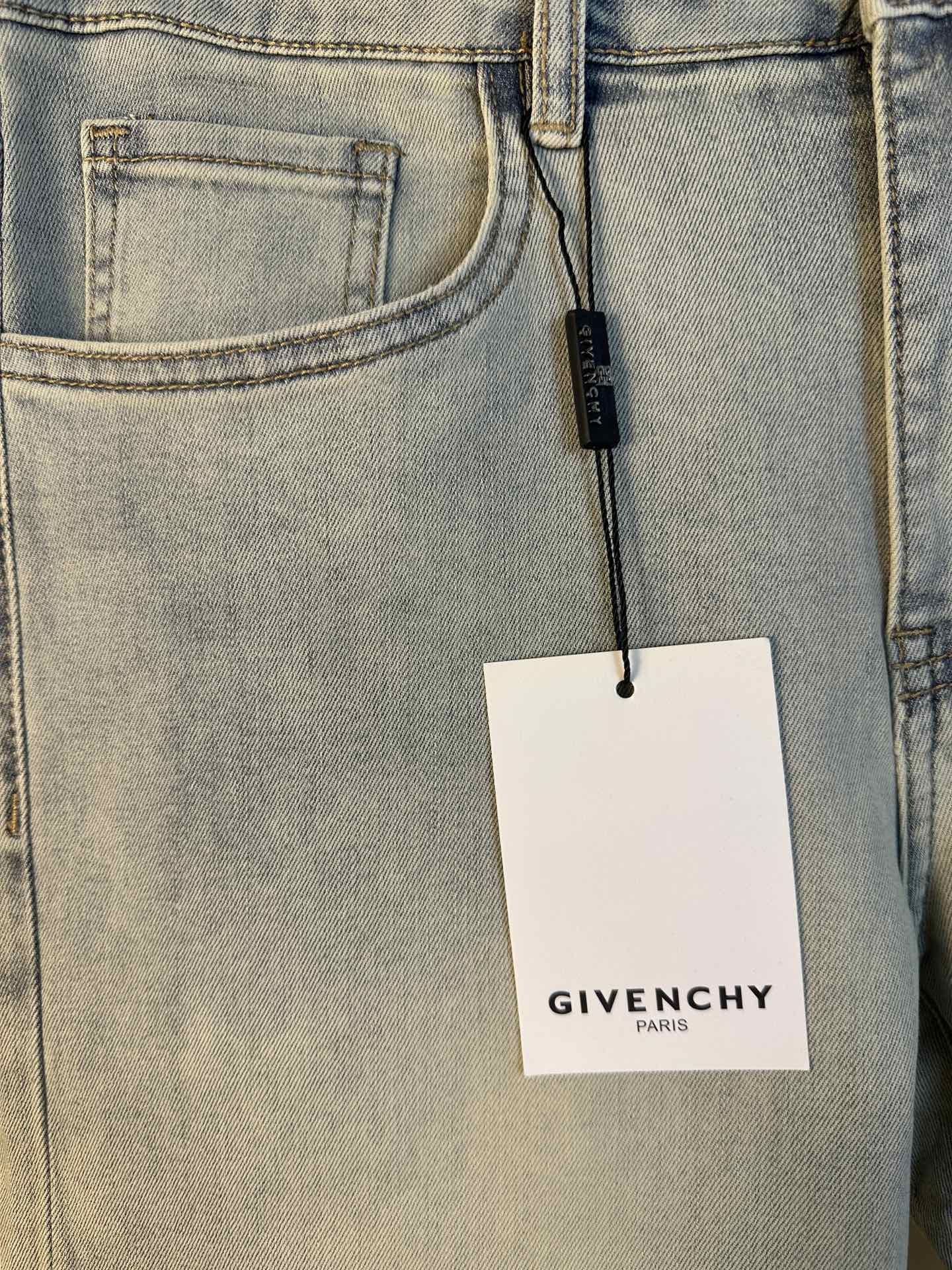 Light-wash denim jeans close-up of front pocket with hanging Givenchy tag