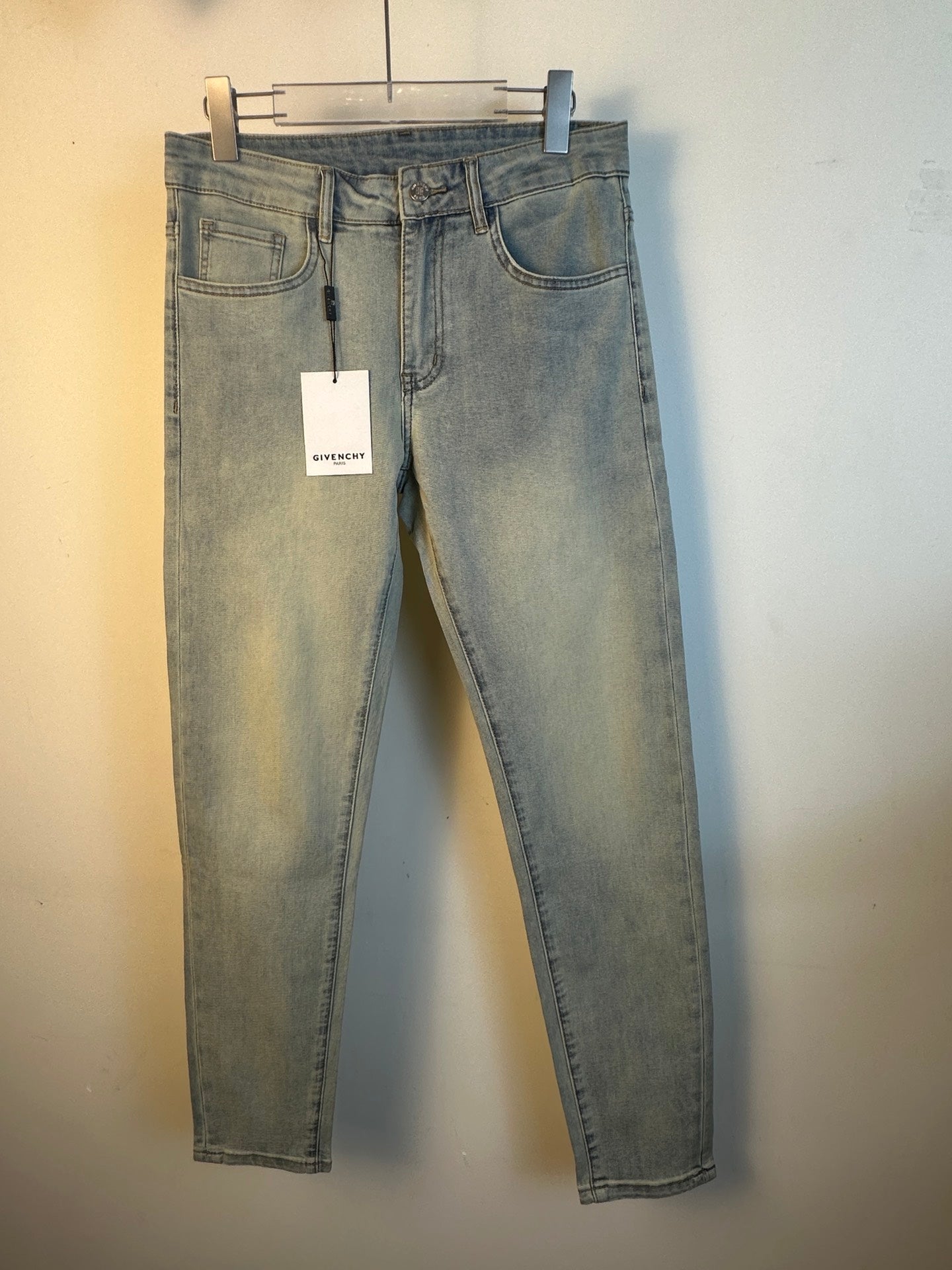 Light-wash denim jeans on a hanger, straight leg with belt loops and hanging product tag