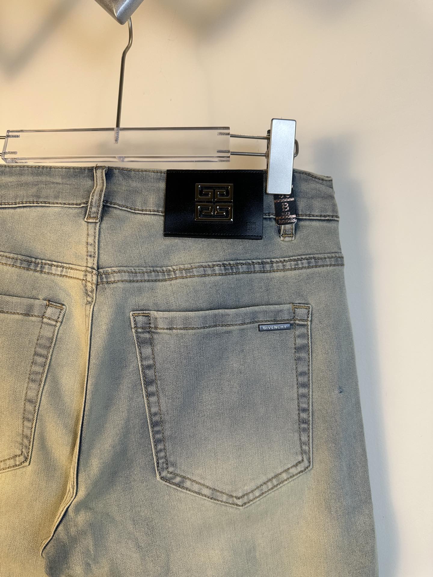 Light-wash denim jeans close-up of back waistband area with logo hardware and pocket