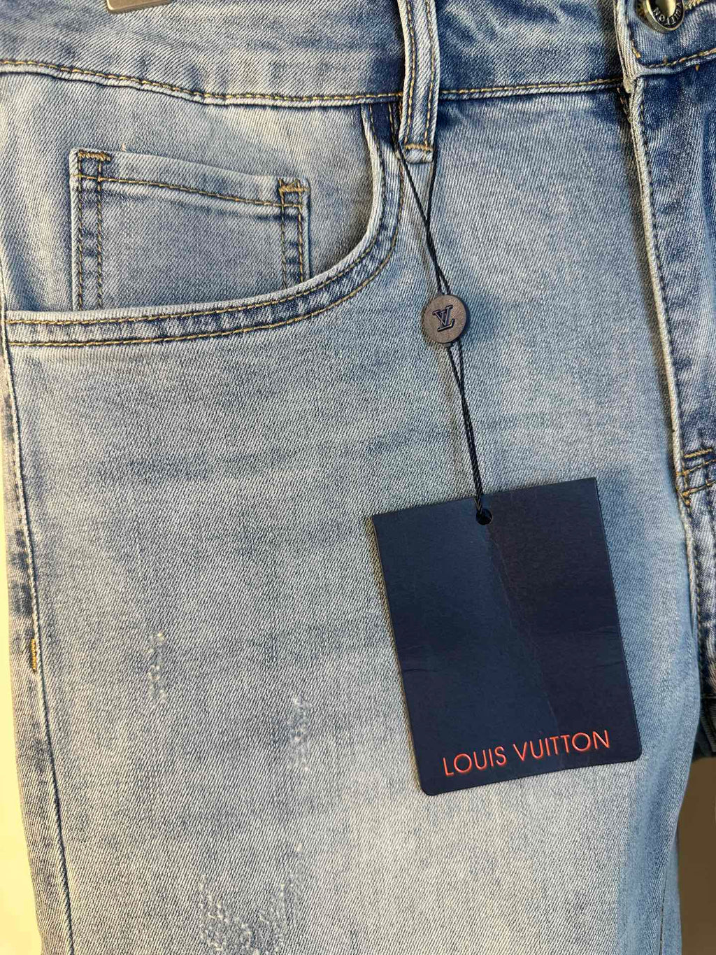 Louis Vuitton denim pants close-up, stitched front pocket and leather brand tag