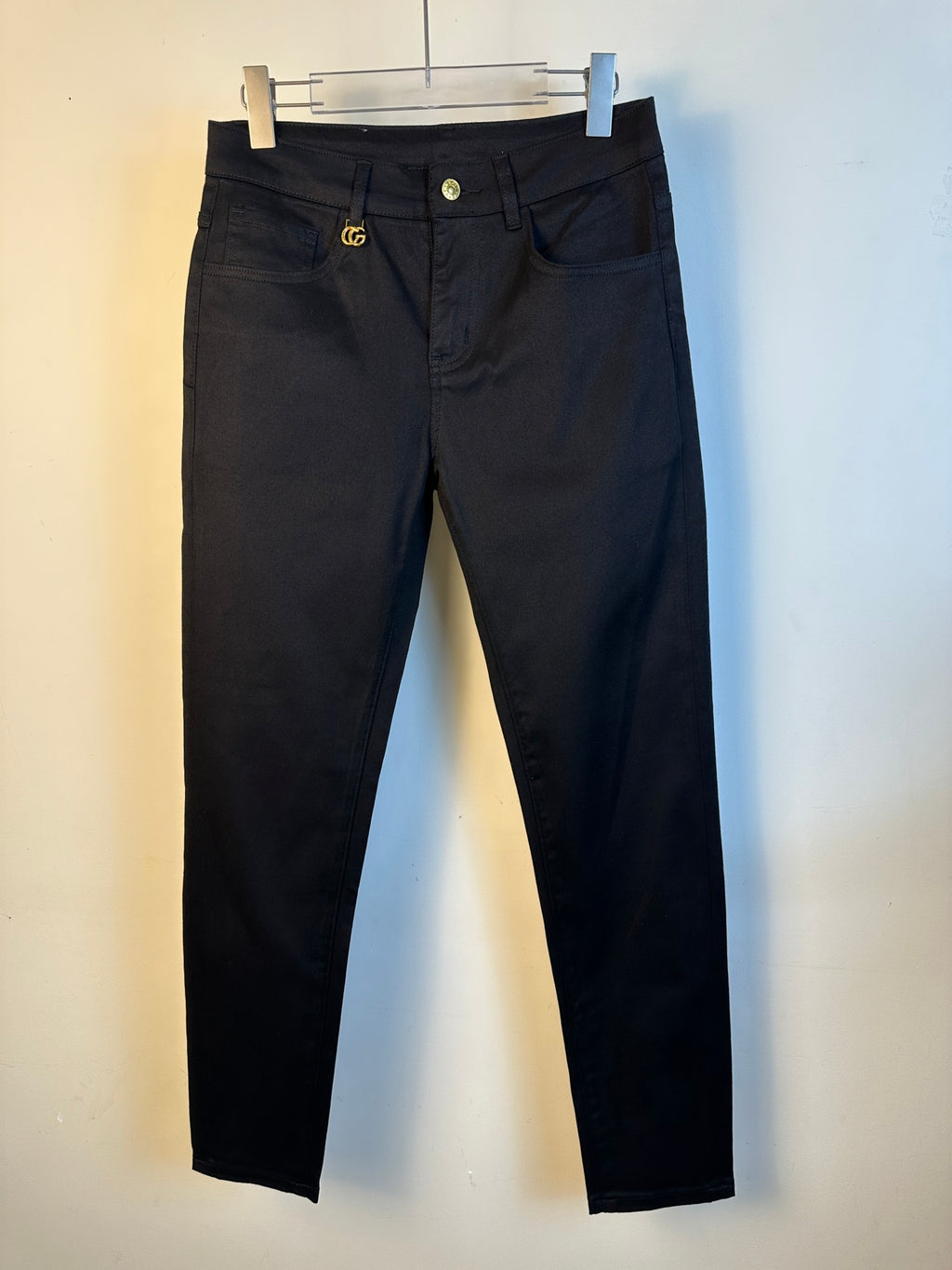 Black straight-leg pants on hanger, front button and belt loops