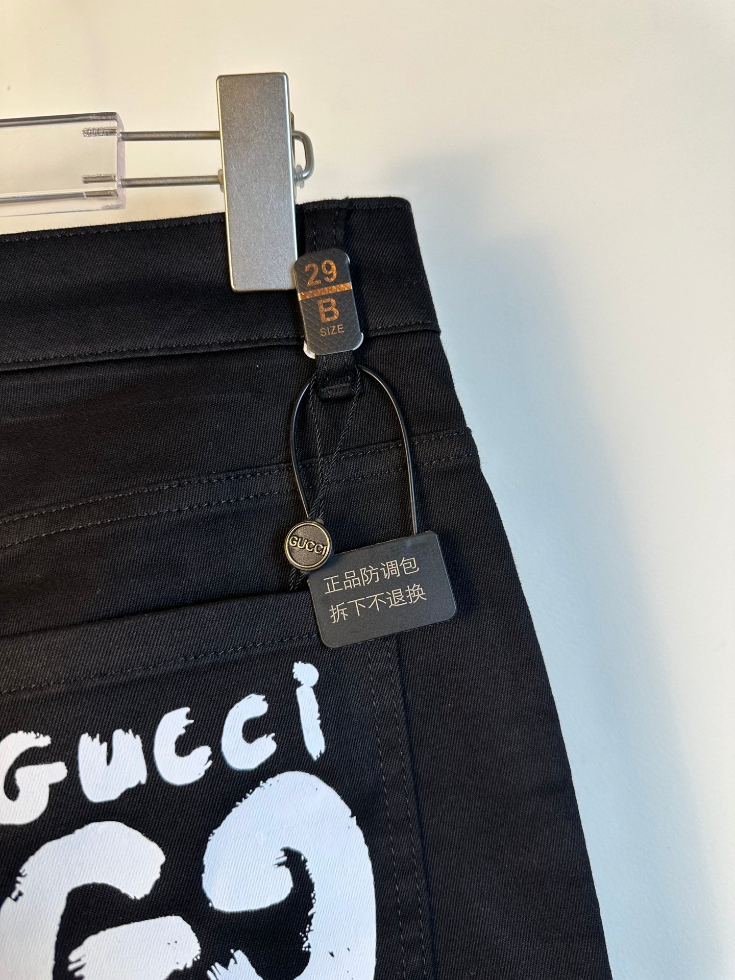 Black pants close-up of white GG69 logo patch and hanging size label