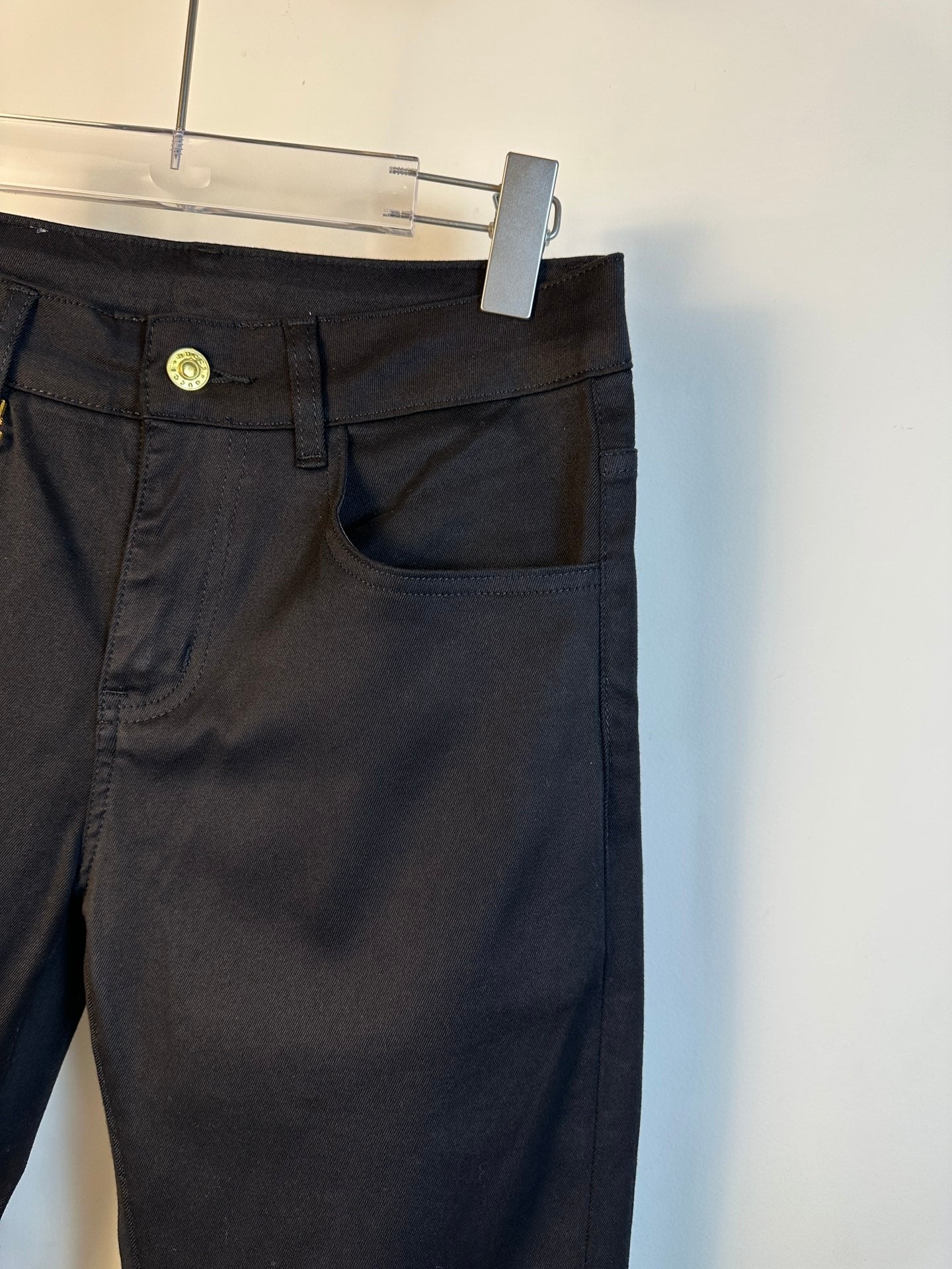 Black pants close-up of front pocket, waistband button, and belt loops