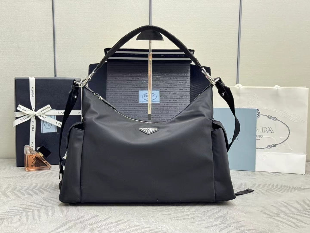 Prada bag in dark nylon with top handles, logo plaque, and zip closure