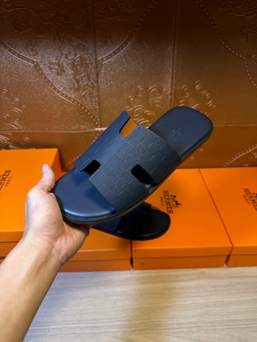 Hand holding blue slide sandals with embossed cross straps