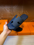 Hand holding blue slide sandals with embossed cross straps
